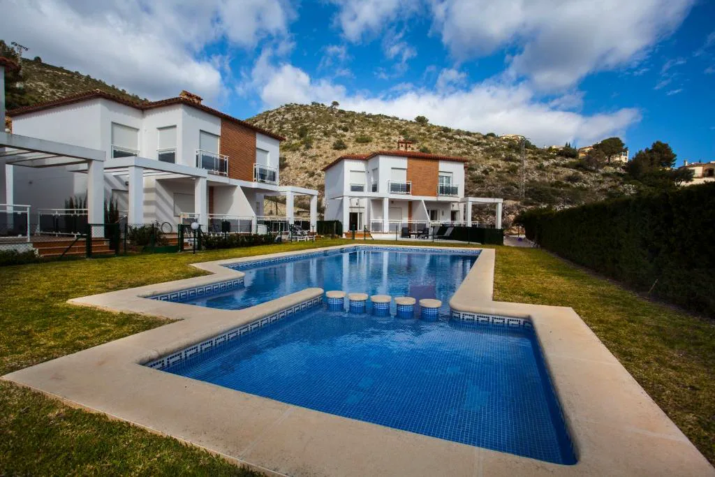 Piscina entre casas blancas y la montaña