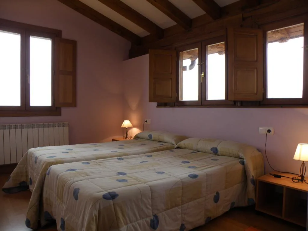 Dormitorio con cama doble y ventanas de madera