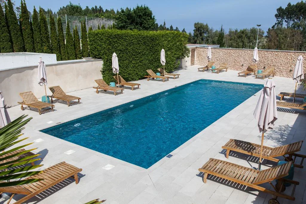 Piscina rectangular con tumbonas de madera y sombrillas