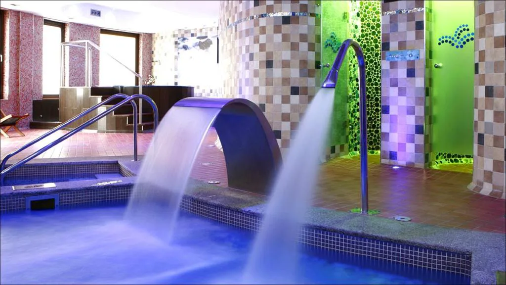 Chorro de agua del spa con paredes de mosaico verde