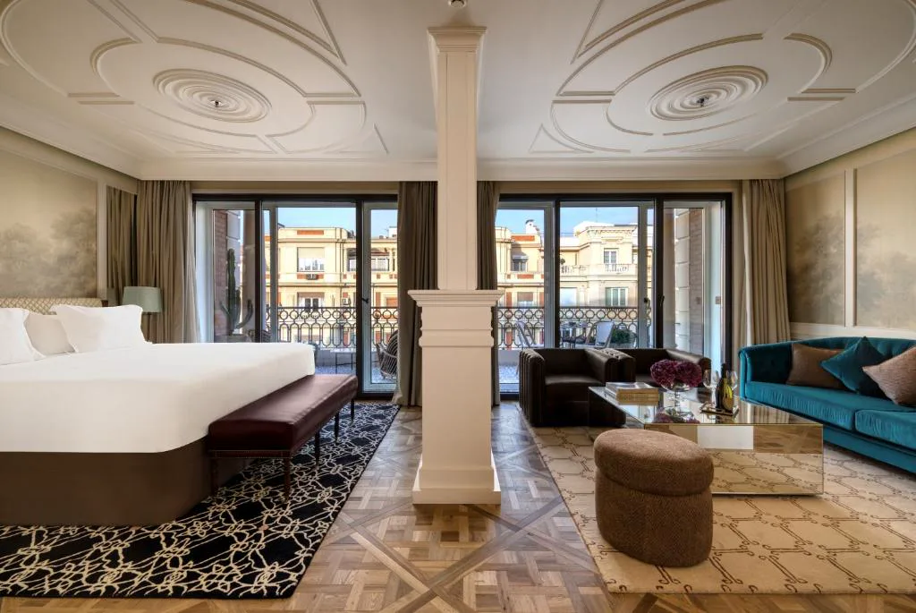 Suite con cama grande, salón y ventanales a un balcón sobre la calle