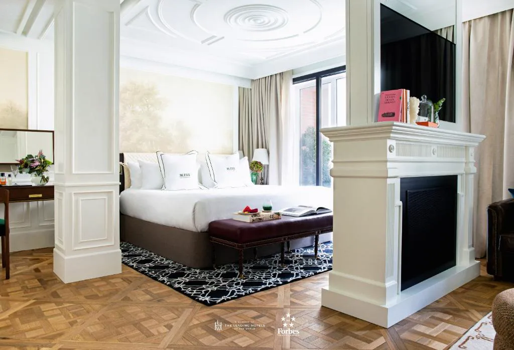 Habitación con cabecero blanco, chimenea decorativa y suelo de parqué