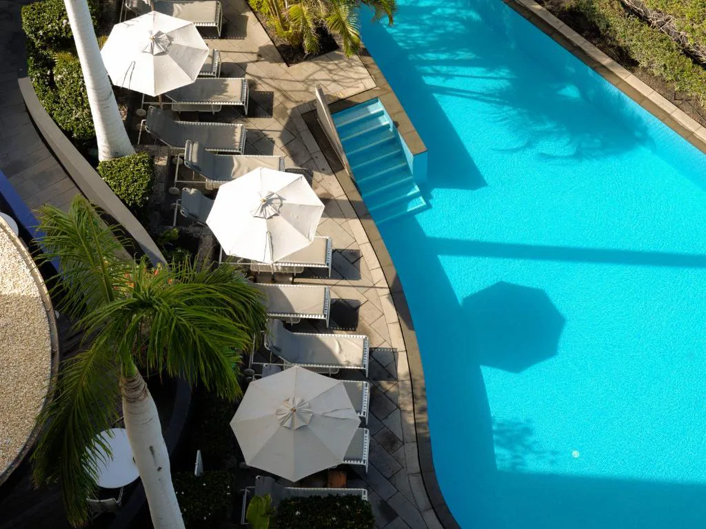 Vista aérea de la piscina exterior con tumbonas y sombrillas blancas, Bohemia Suites