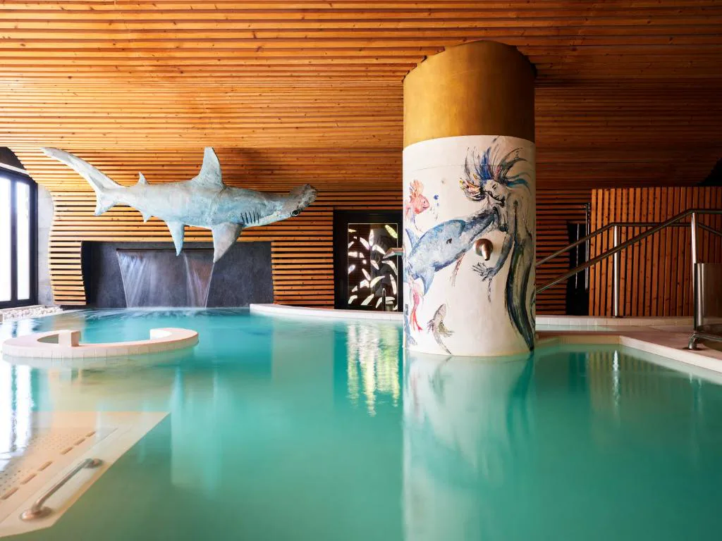 Piscina interior del spa con escultura de tiburón martillo suspendida, Bohemia Suites