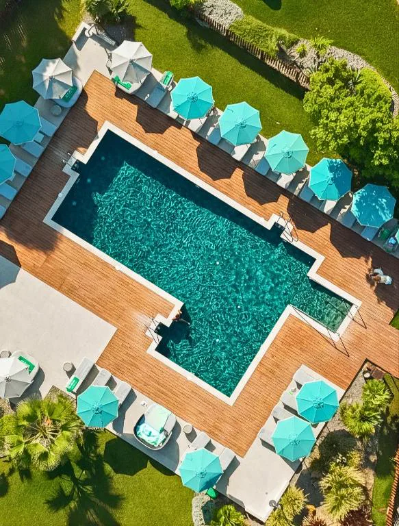 Vista aérea de una piscina rectangular con tumbonas y sombrillas turquesa
