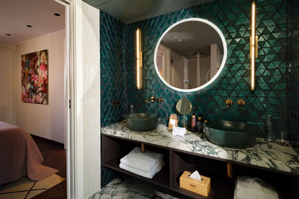 Baño con lavabo verde y espejo redondo