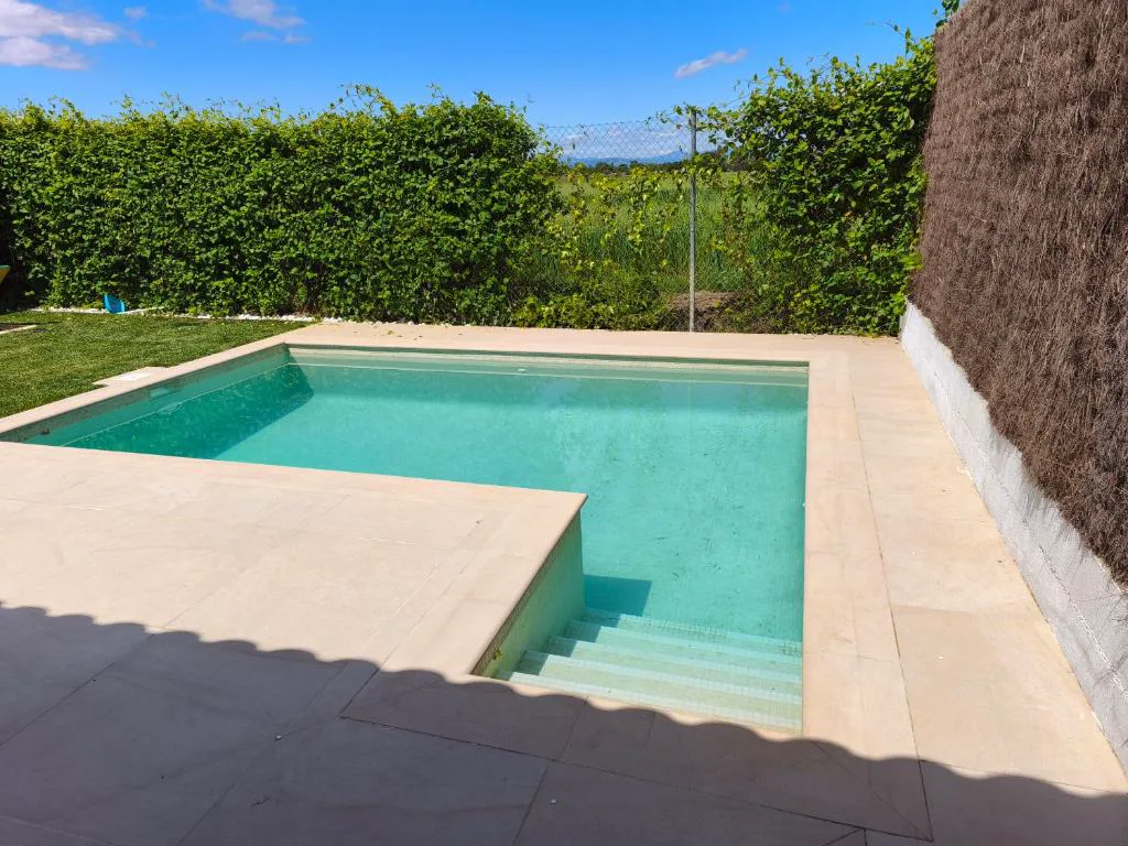 Piscina cuadrada con escalones de piedra clara