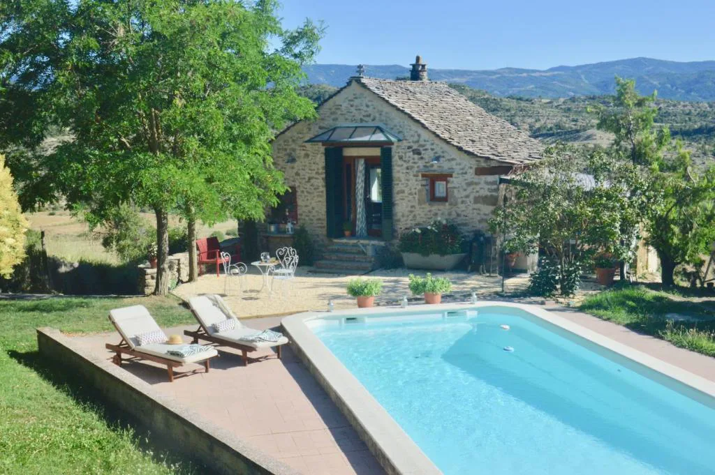 Casa de piedra con piscina y tumbonas en el jardín