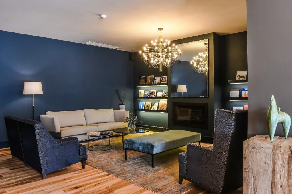 Salón con sofás azul marino y chimenea bajo lámpara de araña, Bordoy Casa Ládico