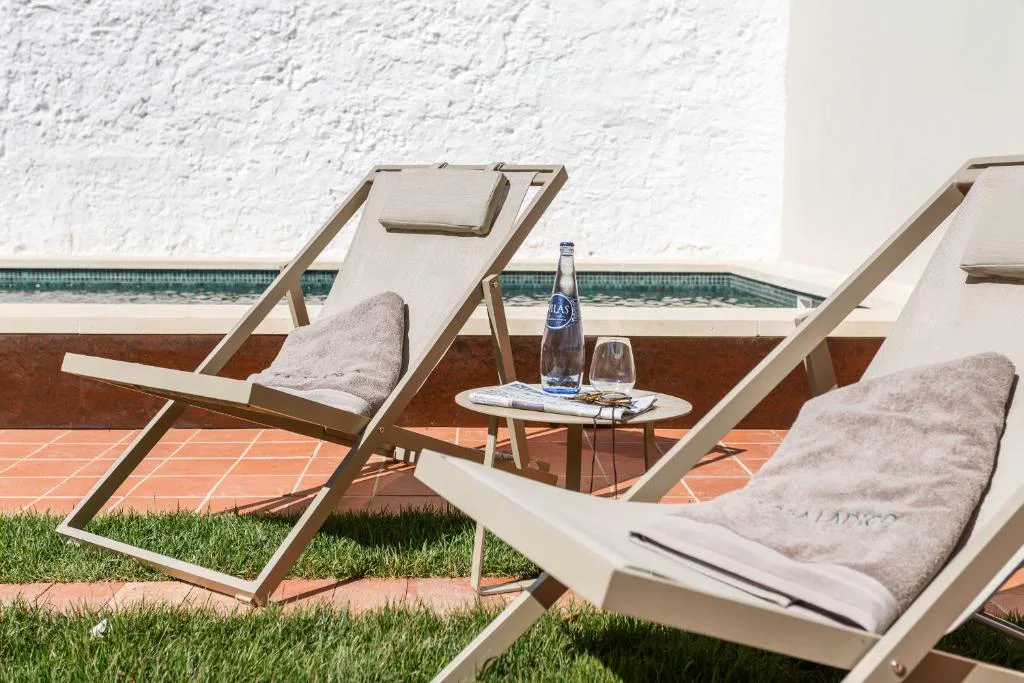 Tumbonas junto a la piscina del patio con toallas y agua mineral, Bordoy Casa Ládico