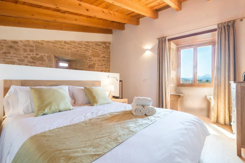 Dormitorio con pared de piedra vista y ventana con vistas al casco antiguo, Bordoy Mostatxins
