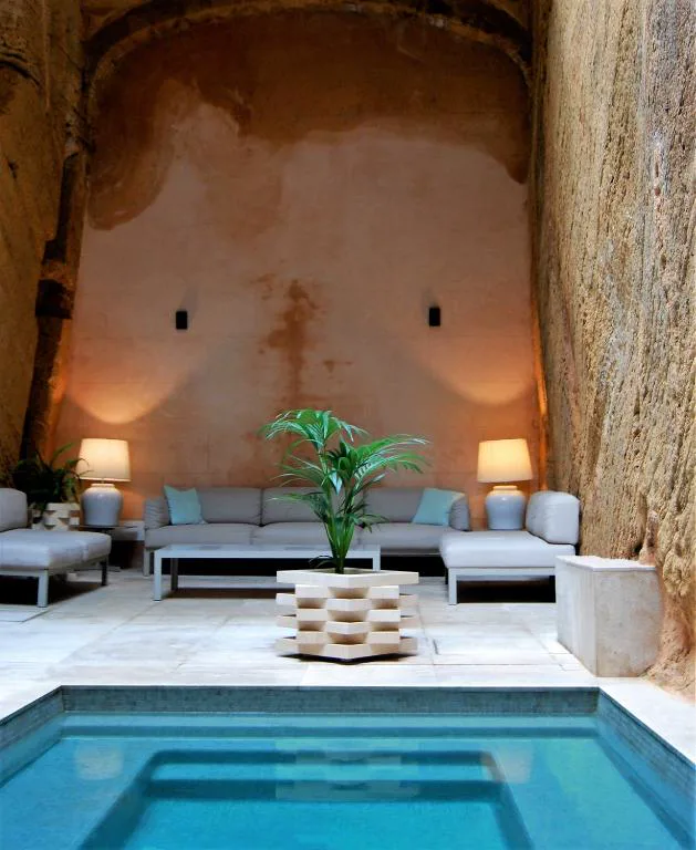 Piscina en el patio de roca excavada, iluminada junto a sofás de exterior, Bordoy Mostatxins