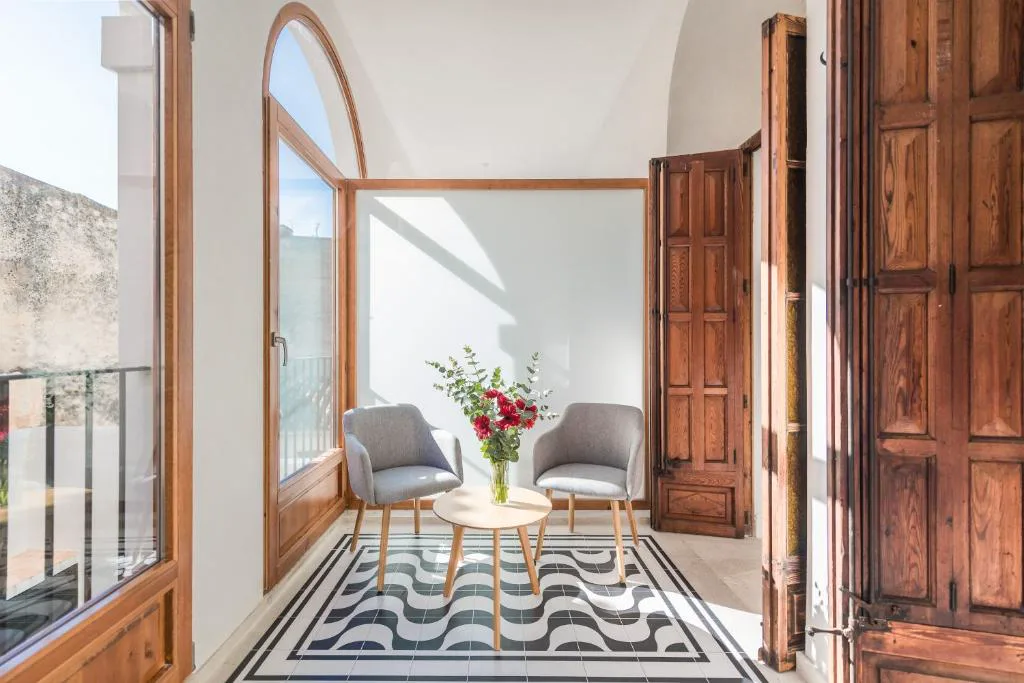 Salón de estar con sillas de mimbre y puerta arqueada de madera tallada, Bordoy Mostatxins