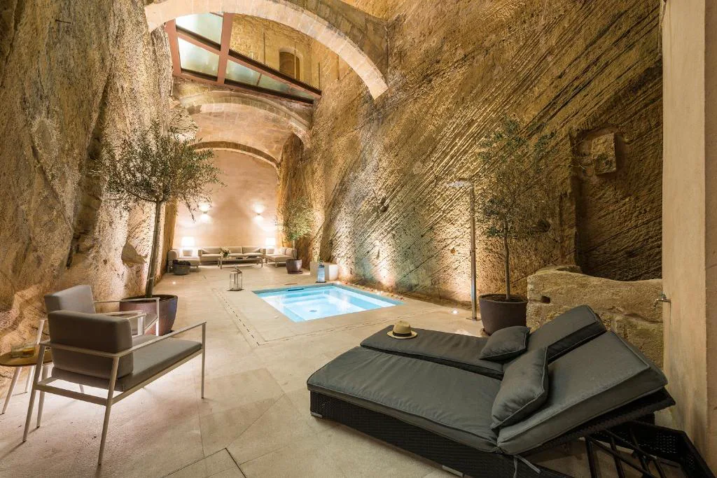 Piscina excavada en un patio de roca con arcos de piedra, Bordoy Mostatxins, en el casco amurallado de Alcúdia, Mallorca