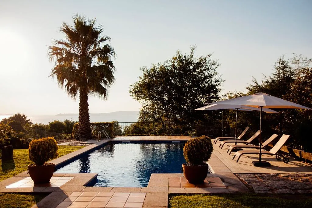 Piscina privada con vistas a la Ría de Pontevedra y una palmera al atardecer, en Bosque de Xarás