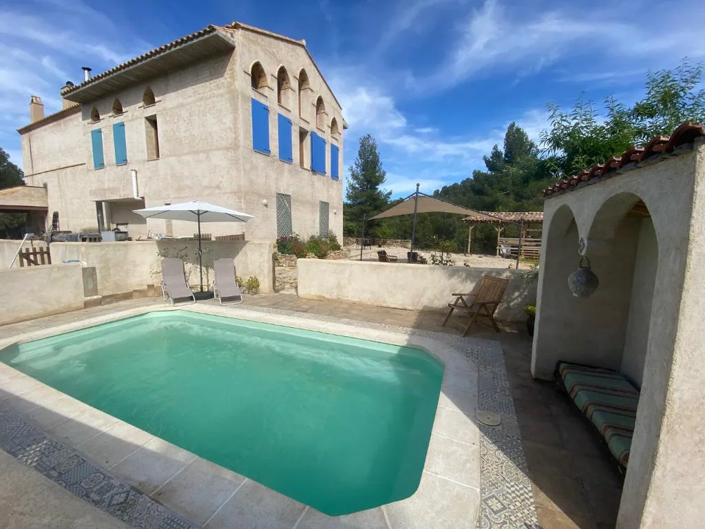 Piscina turquesa junto a una masía de piedra con arcos