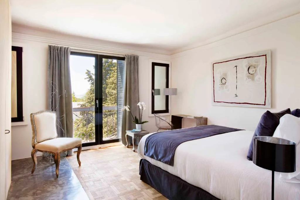 Habitación con ventana a los árboles y cama blanca