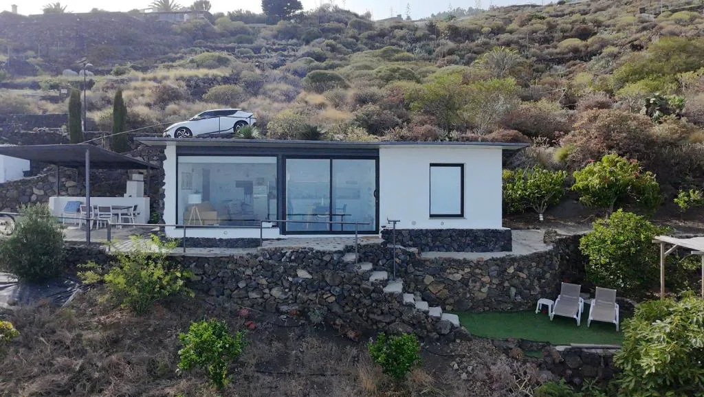 Vista exterior del bungalow con tumbonas blancas y naranjos junto al muro de piedra, Bungalowmirador