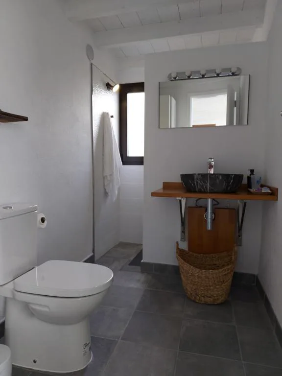 Baño con lavabo de piedra oscura y ducha con mampara de vidrio, Bungalowmirador