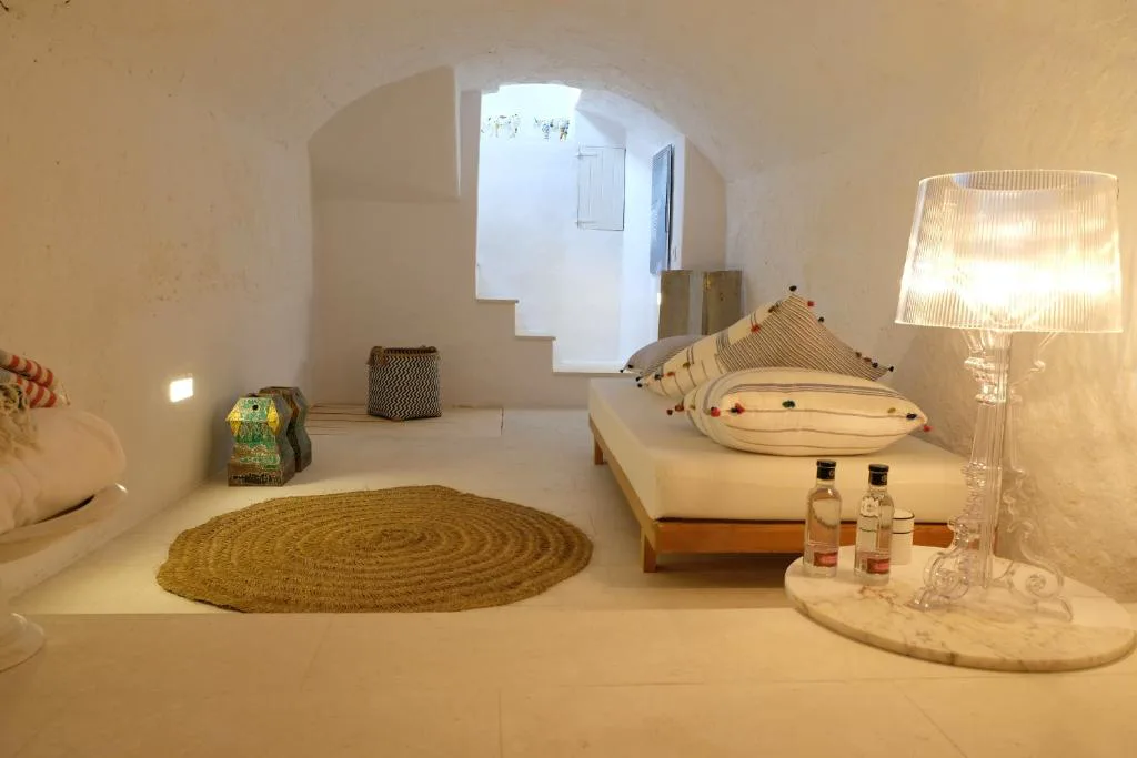 Dormitorio abovedado excavado en piedra con escalera y alfombra circular de fibra natural, Ca na Kika