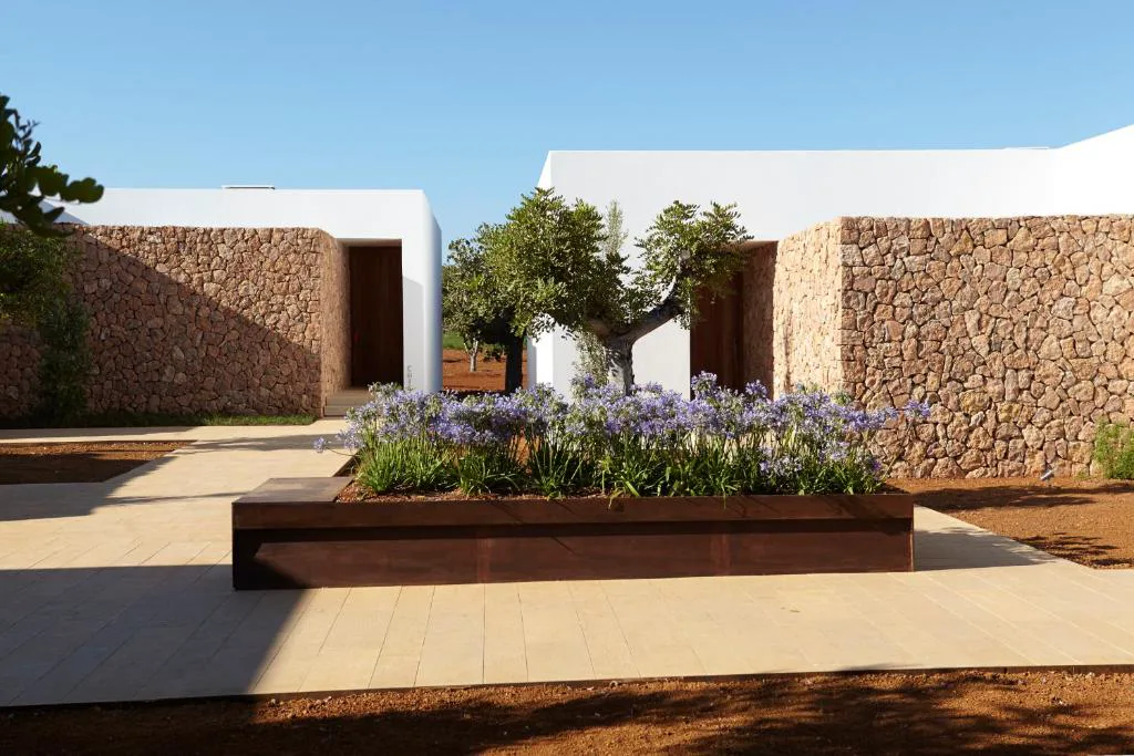 Jardinera con flores moradas entre muros de piedra seca, Ca Na Xica