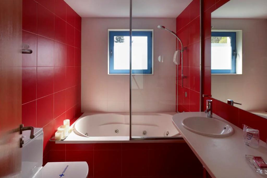 Bañera de hidromasaje con chorros activos en un baño de azulejo rojo, A Cabana de Carmen
