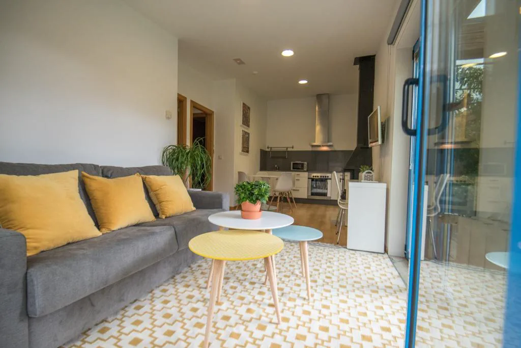 Salón con sofá gris, cojines mostaza y cocina abierta al fondo, A Cabana de Carmen