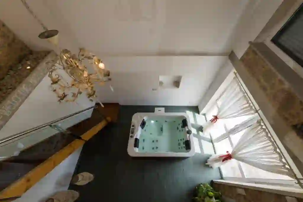 Vista cenital del jacuzzi con candelabro y ventanales con lazos rojos, Cabaña de Nemiña