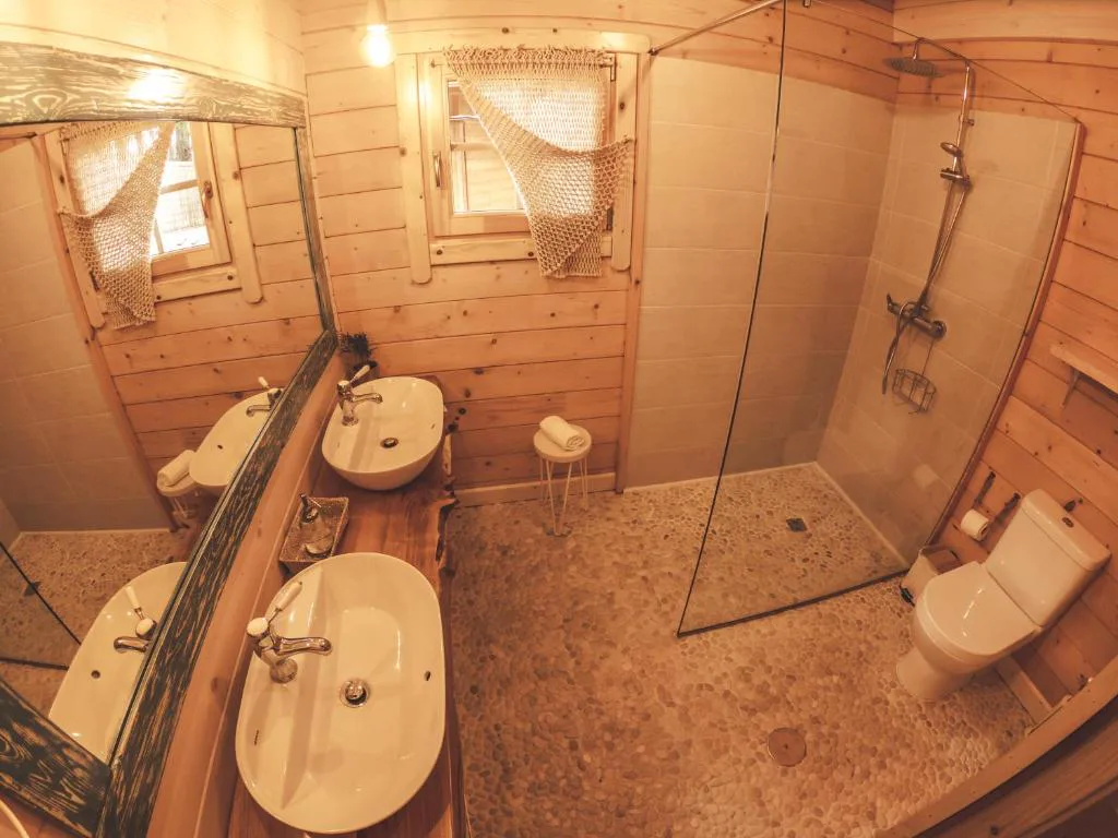 Baño con suelo de guijarros, doble lavabo de piedra y ducha de cristal, Cabanas da Ría