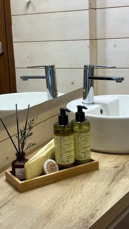Detalle del baño con amenities naturales sobre la encimera de madera, en Cabanas das Chousas