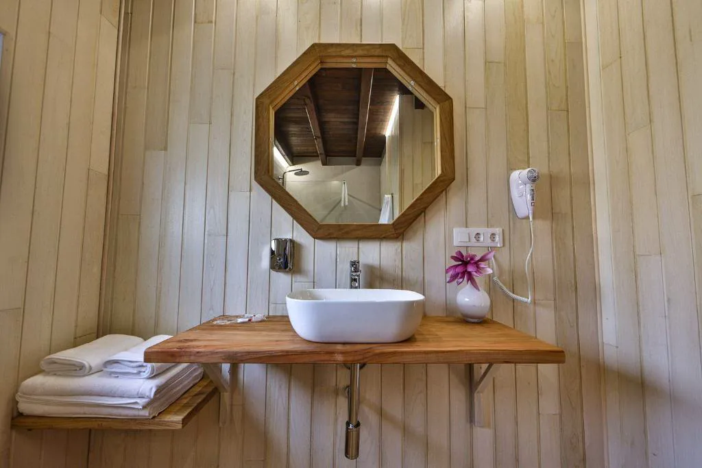 Baño con lavabo de madera maciza y espejo octogonal, Cabañas de Mallas