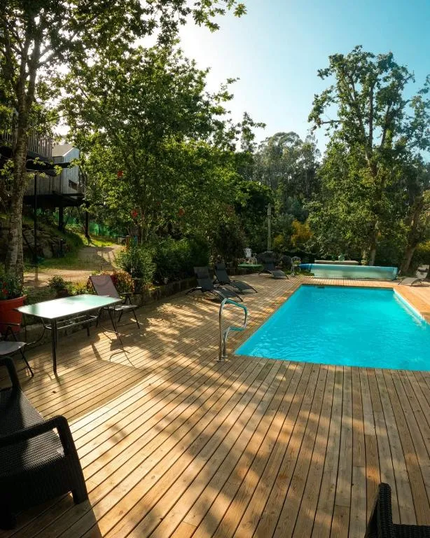 Piscina exterior en terraza de madera rodeada de pinos y eucaliptos, Cabañas de Udra en Bueu