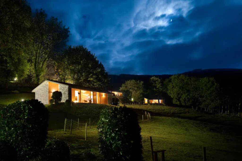 Cabaña iluminada de noche entre árboles
