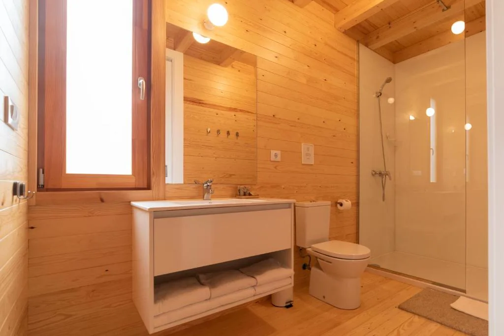 Baño de madera con ducha de cristal y lavabo suspendido, Cabanas Narea