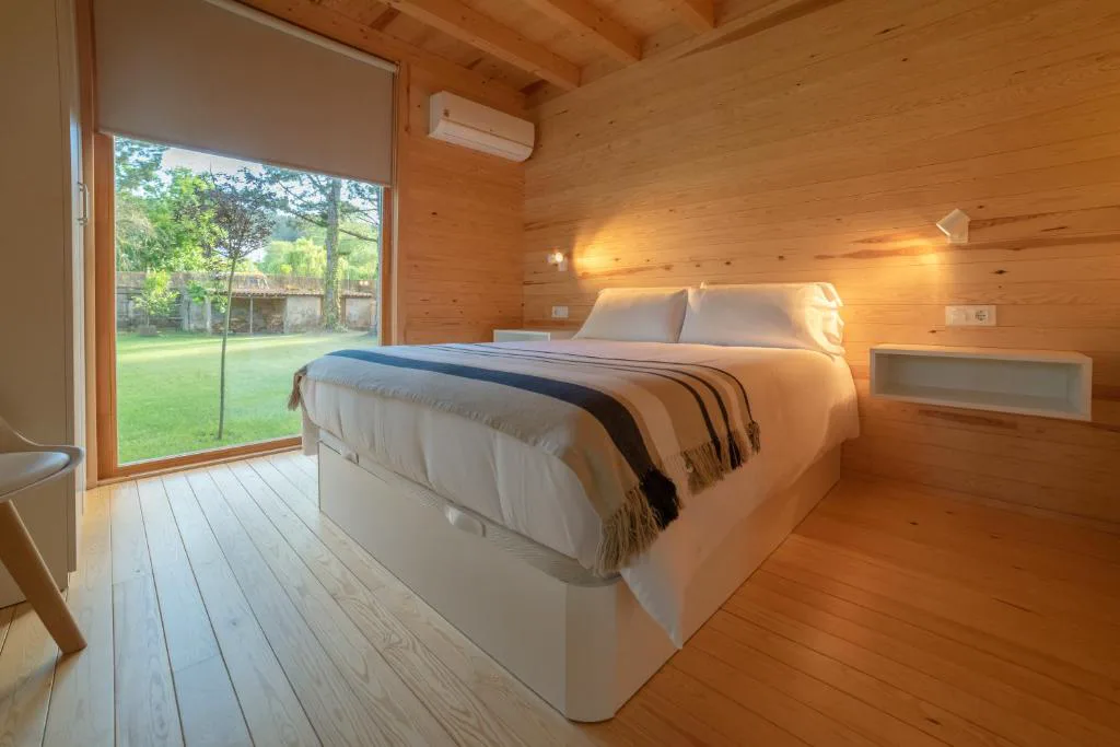 Dormitorio con manta de rayas y vistas al jardín trasero, Cabanas Narea