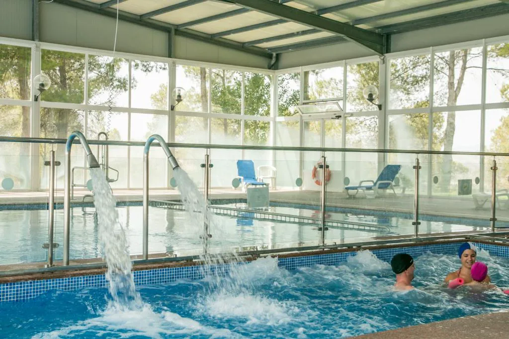 Piscina interior de spa con chorros y ventanales