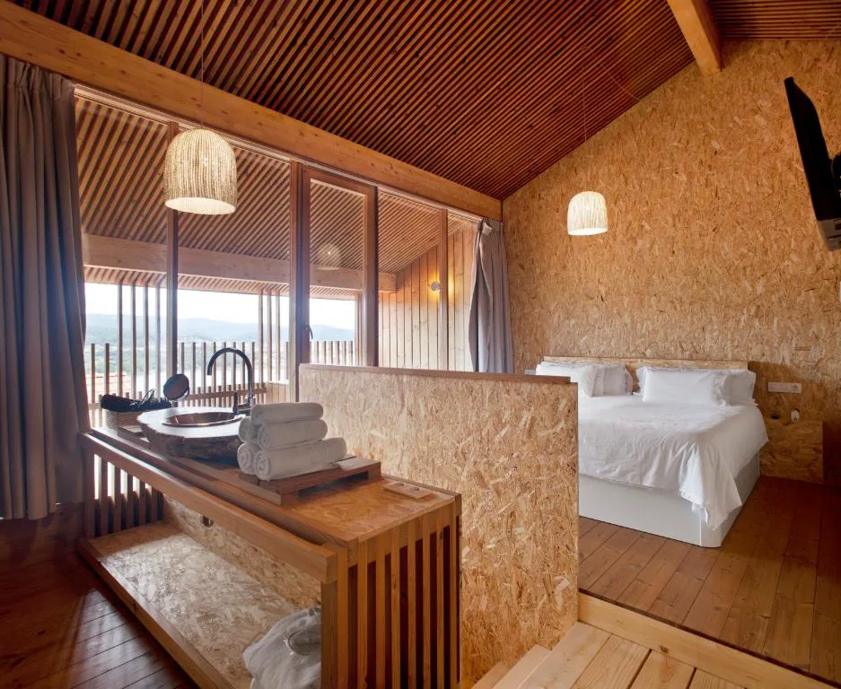 Habitación con lavabo de piedra y ventanales con vistas al bosque, Cabañas con vista a la ría