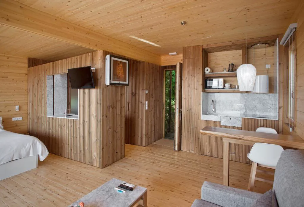 Interior en madera con cocina y zona de estar, Cabañas con vista a la ría