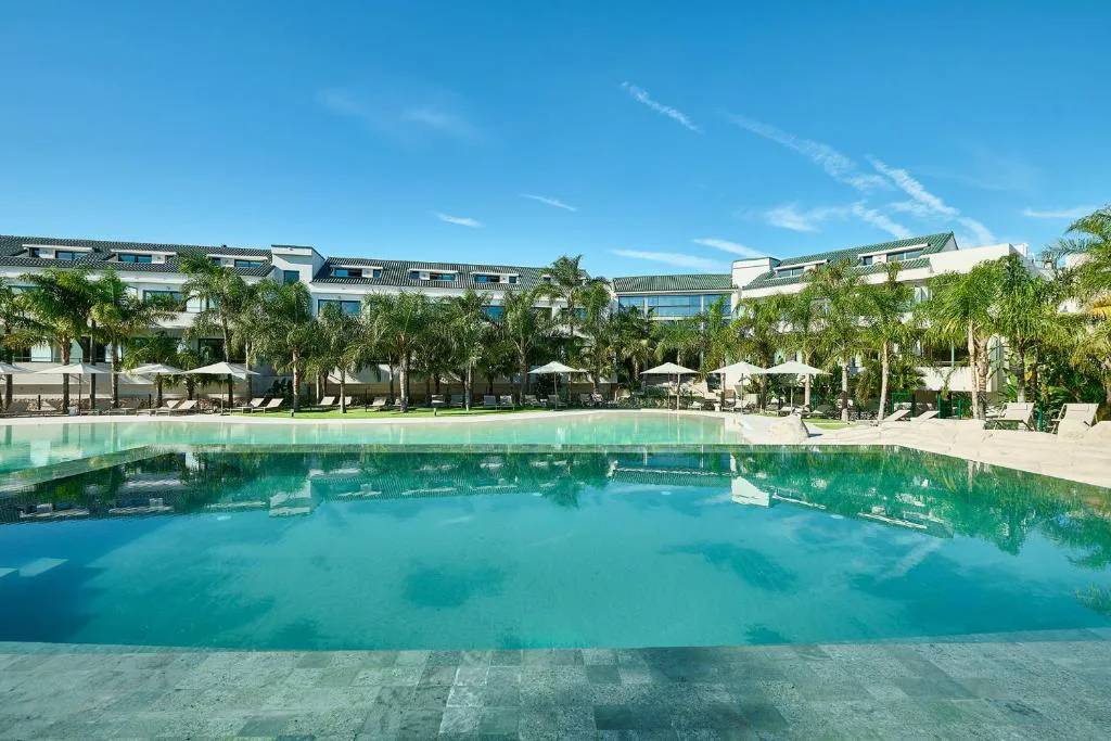 Piscina infinita con tumbonas y vistas a las colinas