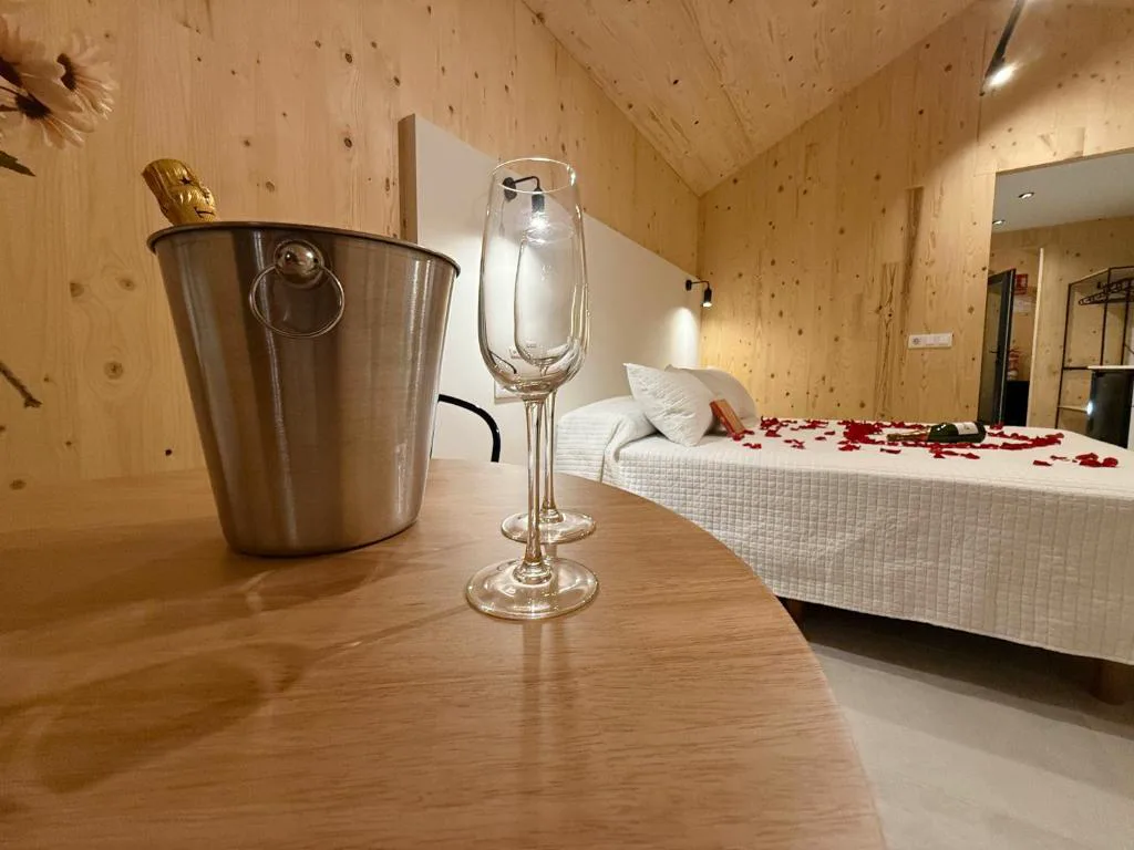 Cubitera con champán, copas y pétalos de rosa sobre la cama, Camiño do Mar