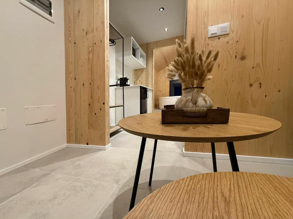 Mesa redonda de madera con ramo seco, cocina y bañera al fondo, Camiño do Mar