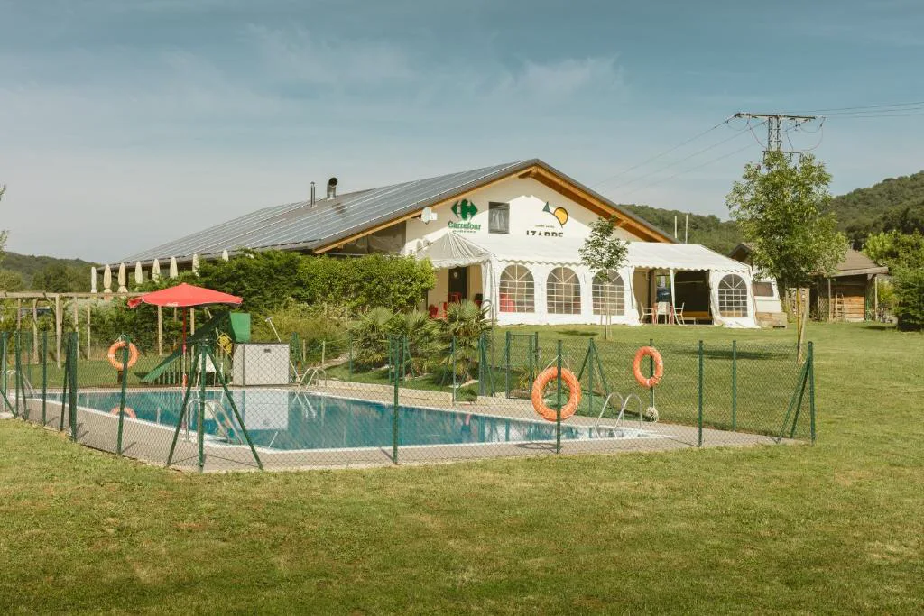 Piscina vallada junto al edificio principal del camping