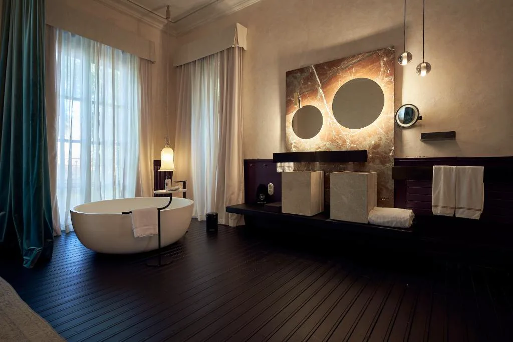 Bañera exenta junto a cortinas de terciopelo verde en la suite, Can Bordoy Grand House