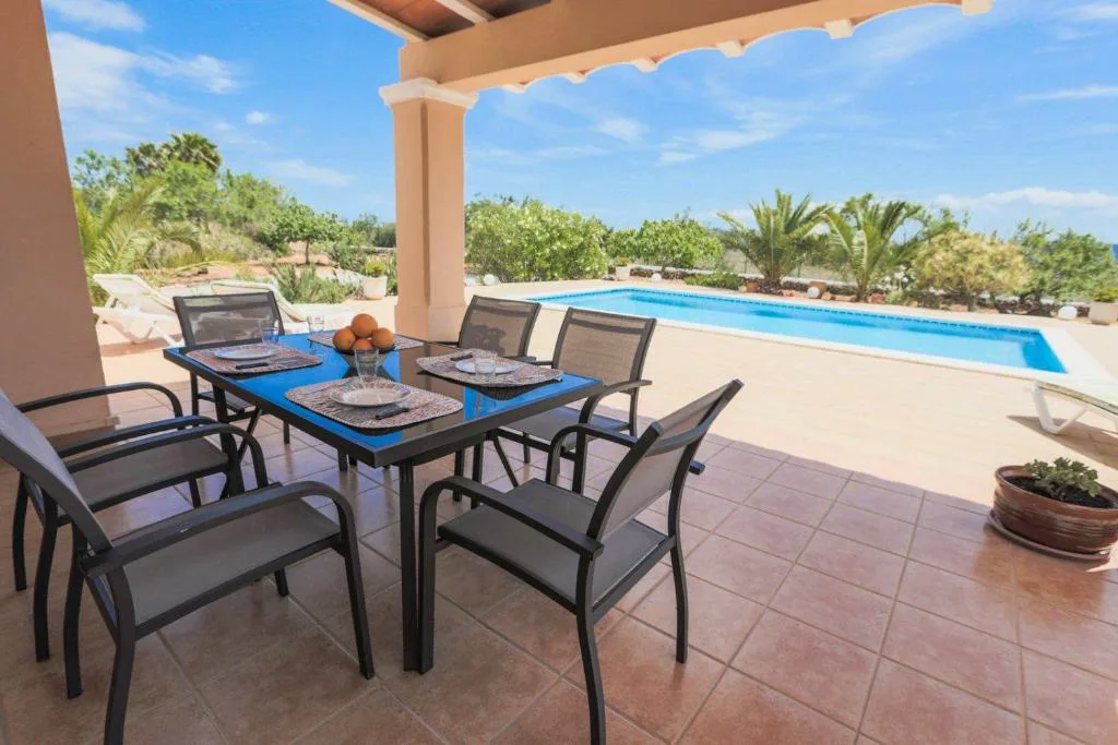 Terraza porticada con mesa de comedor junto a la piscina, Can Furnet