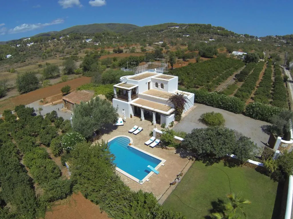 Vista aérea de la finca ibicenca de dos plantas con piscina rodeada de naranjos, Can Gat, en Sant Carles de Peralta, Ibiza
