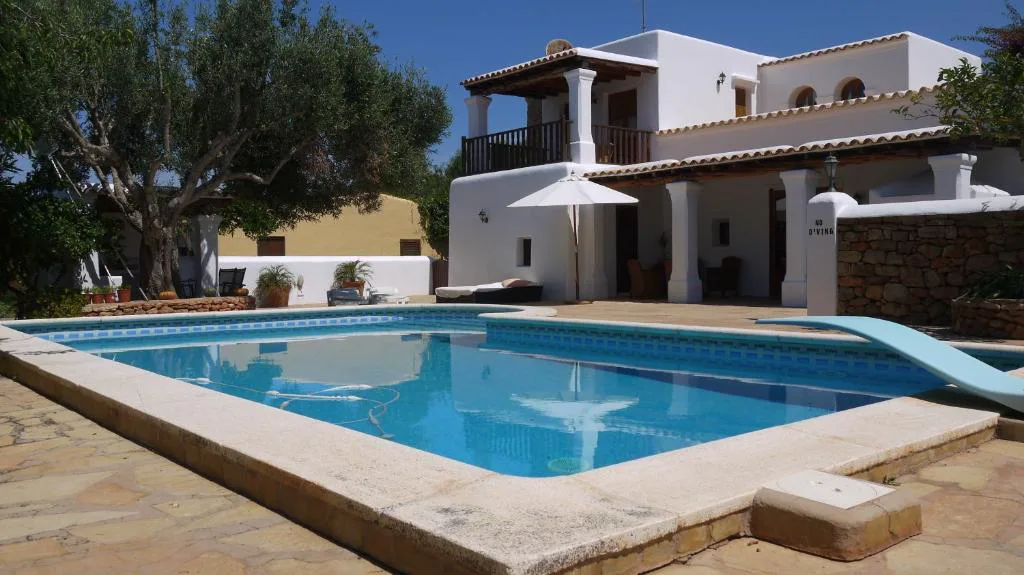Piscina junto a la fachada blanca con balcón de madera y sombrilla, Can Gat