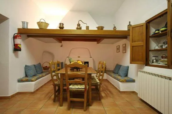 Rincón de comedor tradicional con bancos de obra y utensilios de cobre antiguos, Can Gat