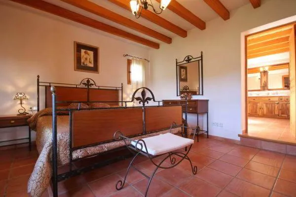 Dormitorio con cabecero de forja y espejo antiguo junto al baño, Can Gat