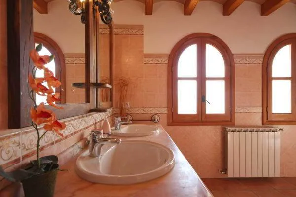 Baño con doble lavabo de mármol y ventanas de arco de medio punto, Can Gat