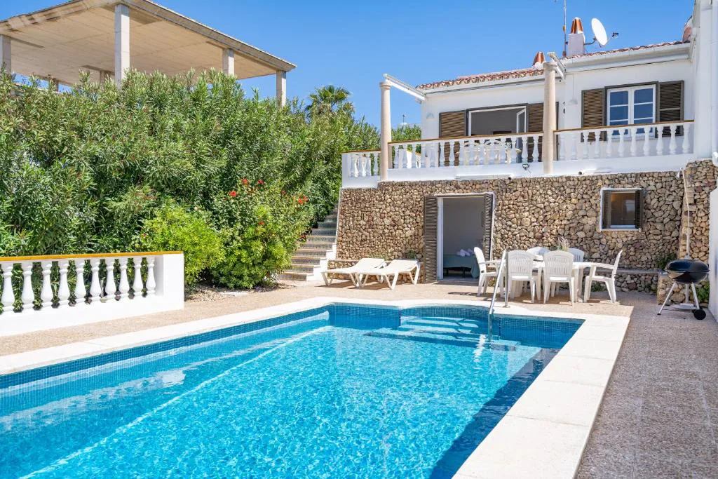 Piscina privada con muro de piedra y porche cubierto junto a la casa, Can Poriol